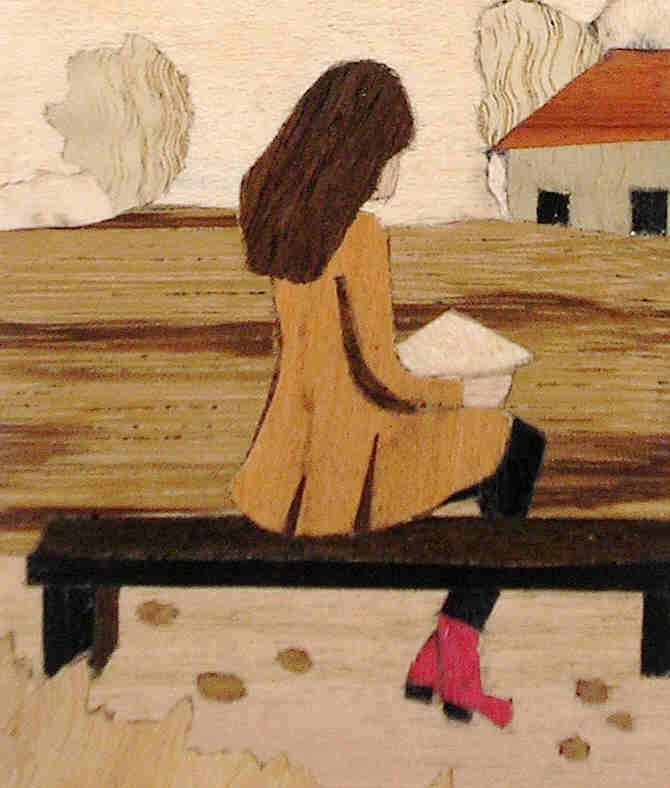 marquetry picture of a girl sittin on a bech, reading